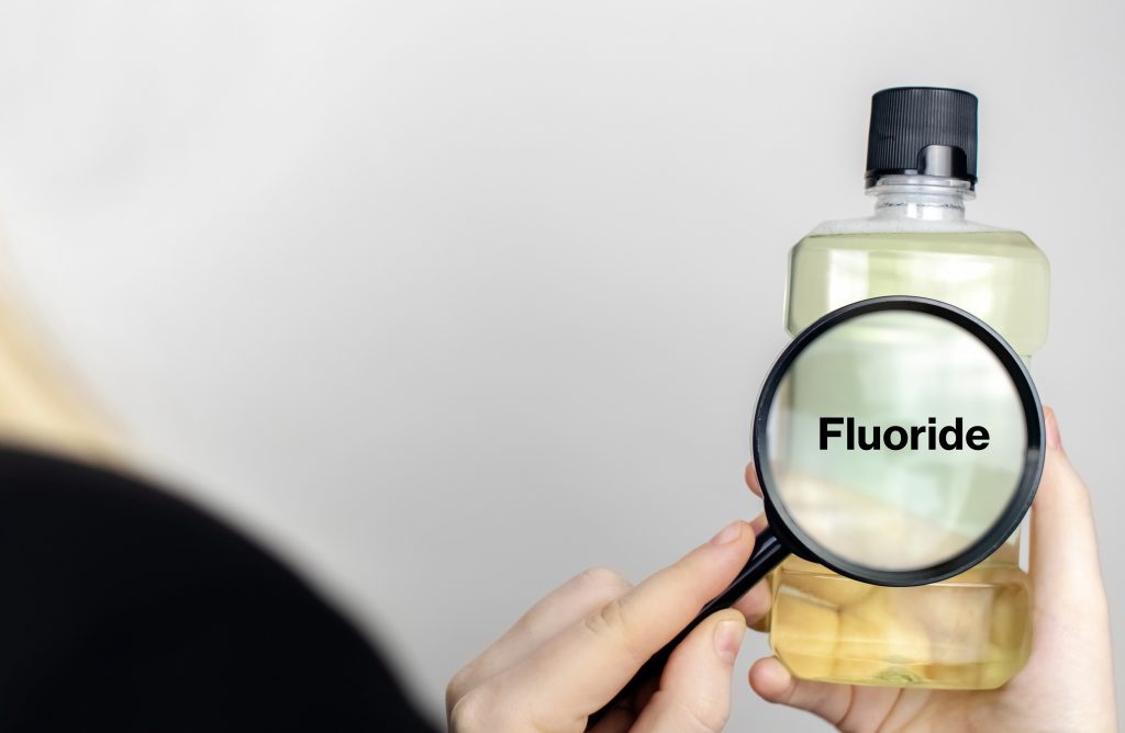 a bottle of mouthwash with fluoride being examined through magnifying glass